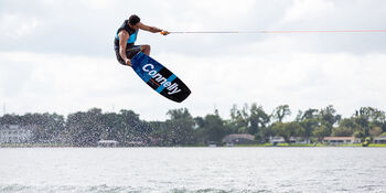A man is pulled by a boat and flies above the water after catching a wave on his wakeboard.