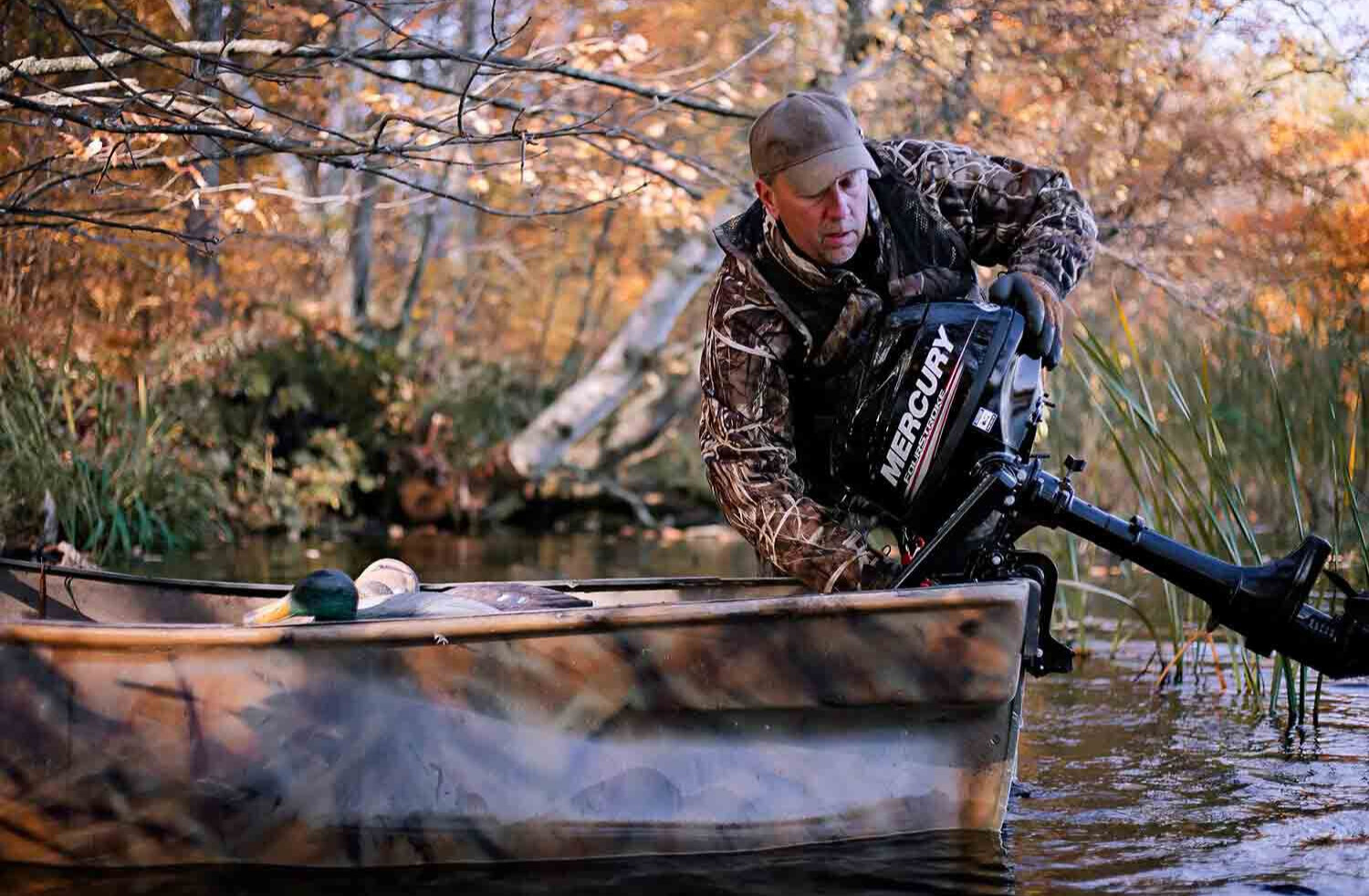 person attaching a small Mercury outboard to a fishing boat