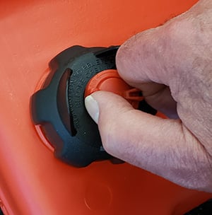 Thumb and forefinger rotating red button on West Marine/Moeller EPA fuel tank cap