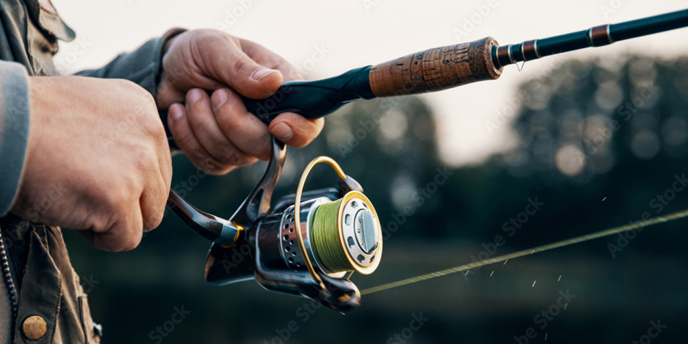 Angler holding a spinning reel while fishing inshore saltwater