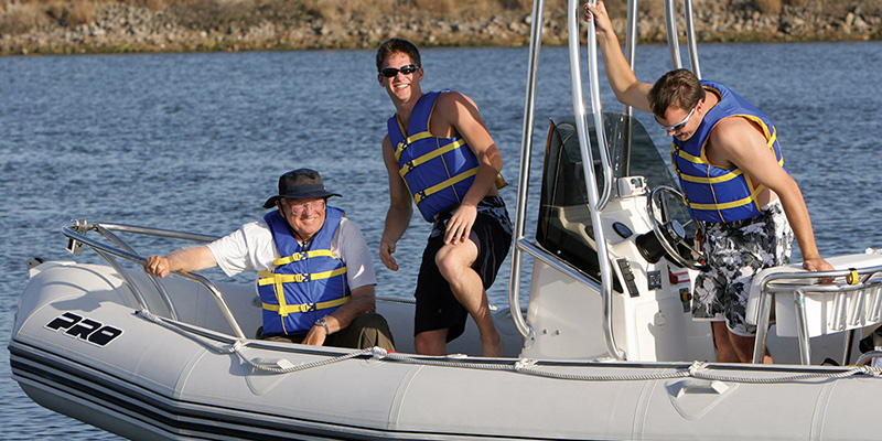 three men in inflatable boat wearing life jackets