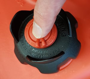 Finger pressing red center button on multi-function cap of West Marine Moeller EPA fuel tank to release internal pressure before connecting fuel line
