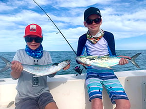 Two boys, each showing off a Spanish mackerel.