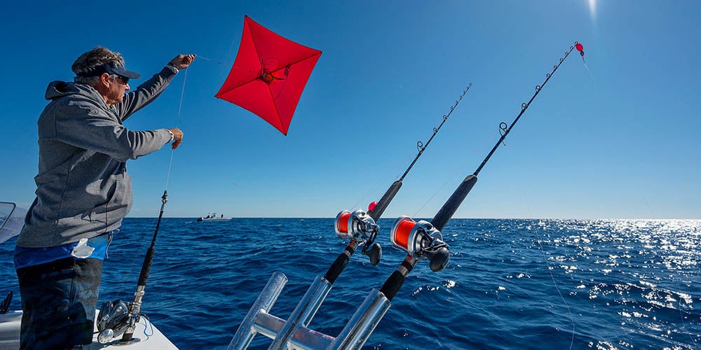 Angler launching a fishing kite from an offshore boat to present live bait at the surface