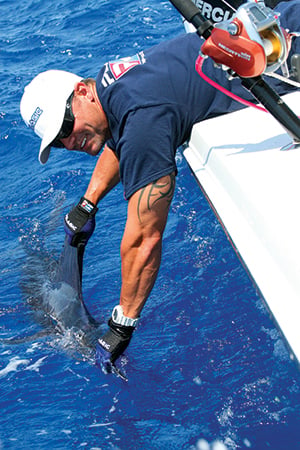 Angler holding a catch in the water next to the boat