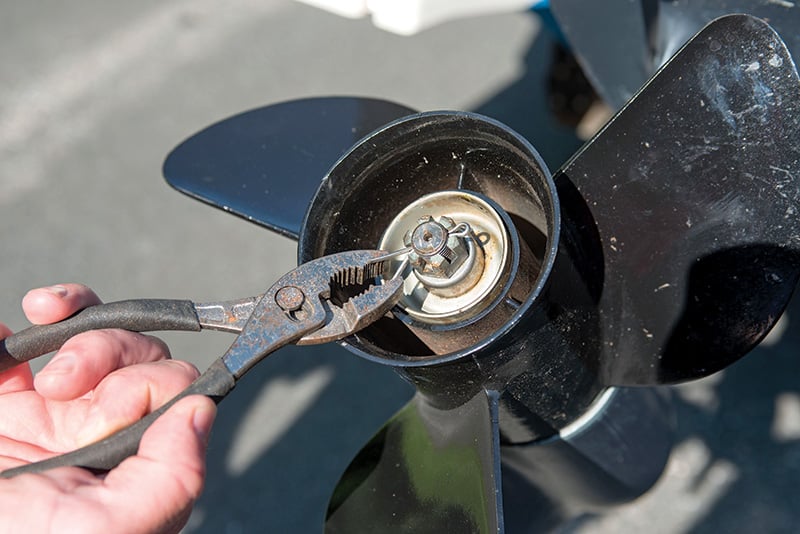 person removing the cotter pin from an outboard prop nut