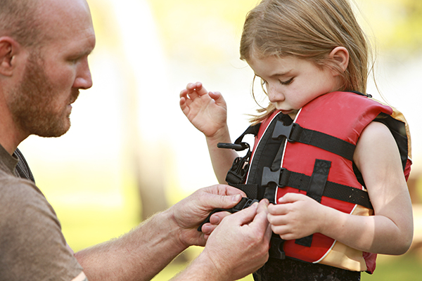 Father putting life jacket on daughter
