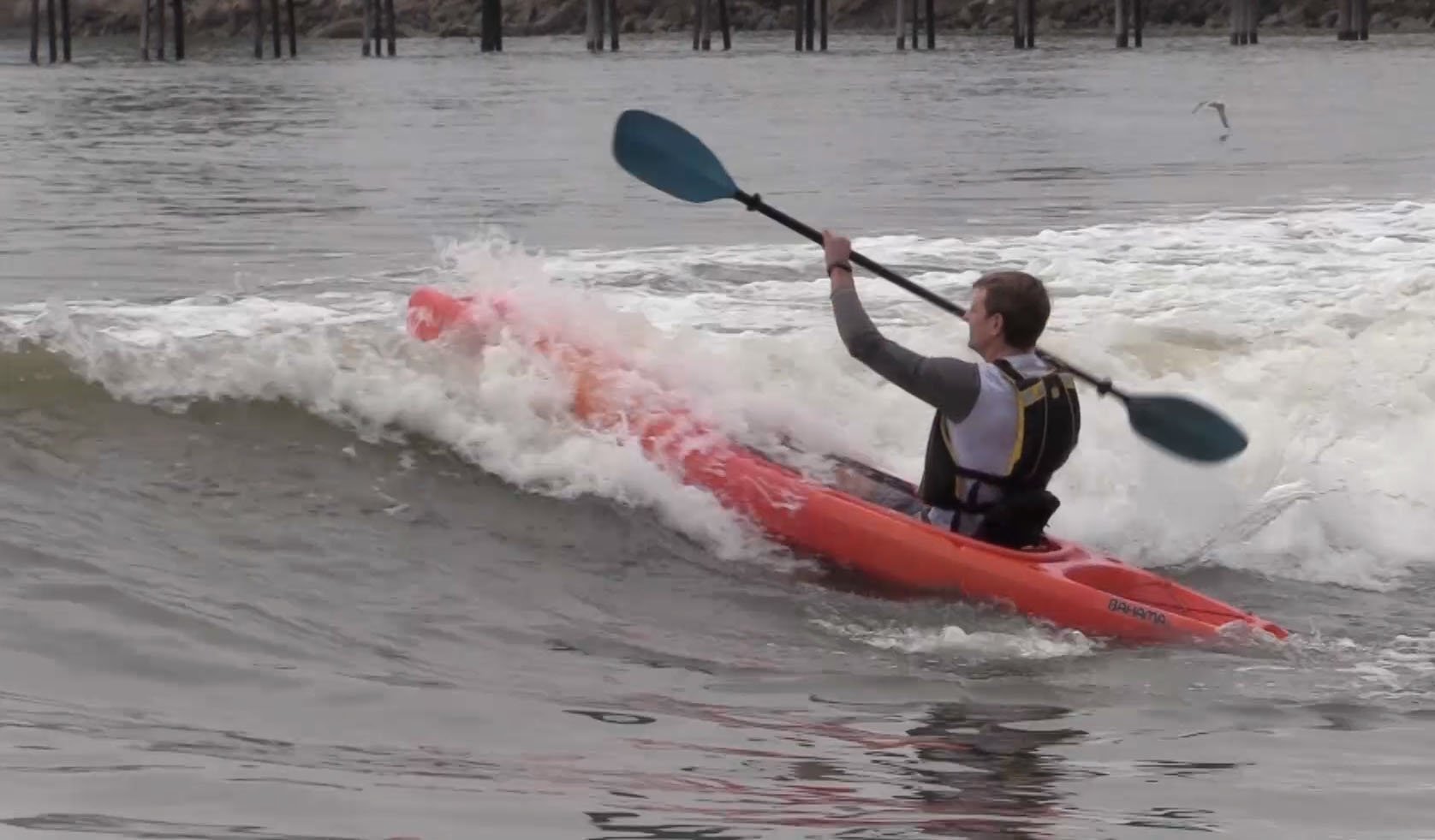 Man paddling kayak over breaking wave