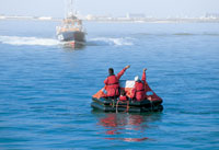 boaters on a liferaft signaling for help
