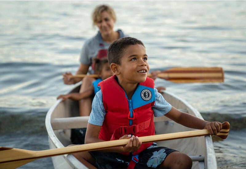 Young boy wearing Lil' Legends life jacket in canoe