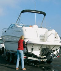 Person checking the tension on the tiedown straps after pulling out the boat
