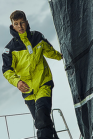 Man wearing OS25 jacket standing on bow of sailboat
