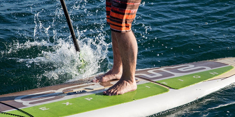 Person riding a stand-up paddle board with paddle