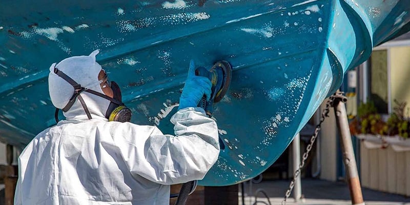 Man disc sanding hull with visible blisters