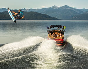 Wakeboarder jumping with JL Audio wake tower speakers in the background.