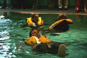 3 people testing life vests in the pool at a safety-at-sea seminar