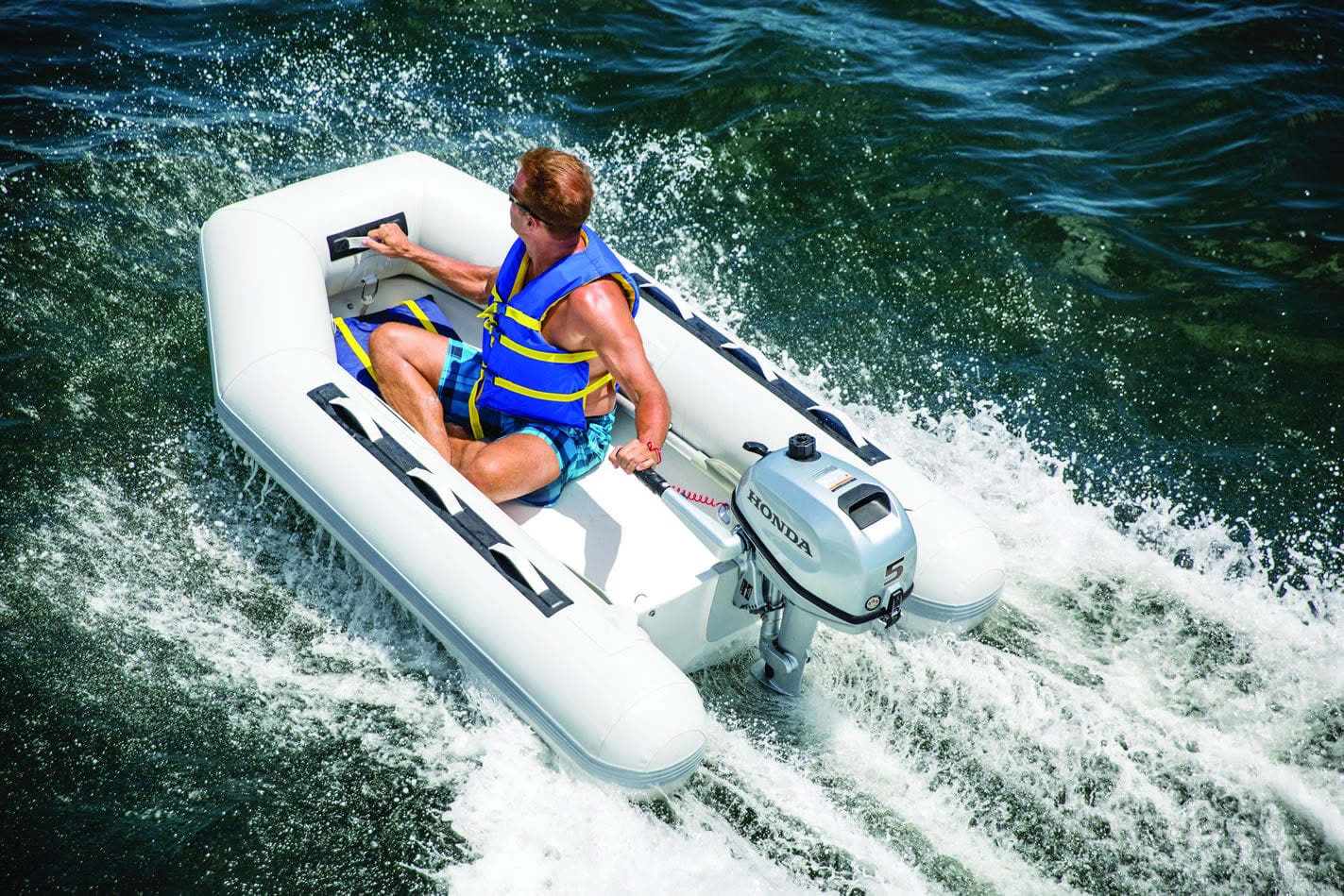 a 5 horsepower honda outboard attached to an inflatable boat moving through the water