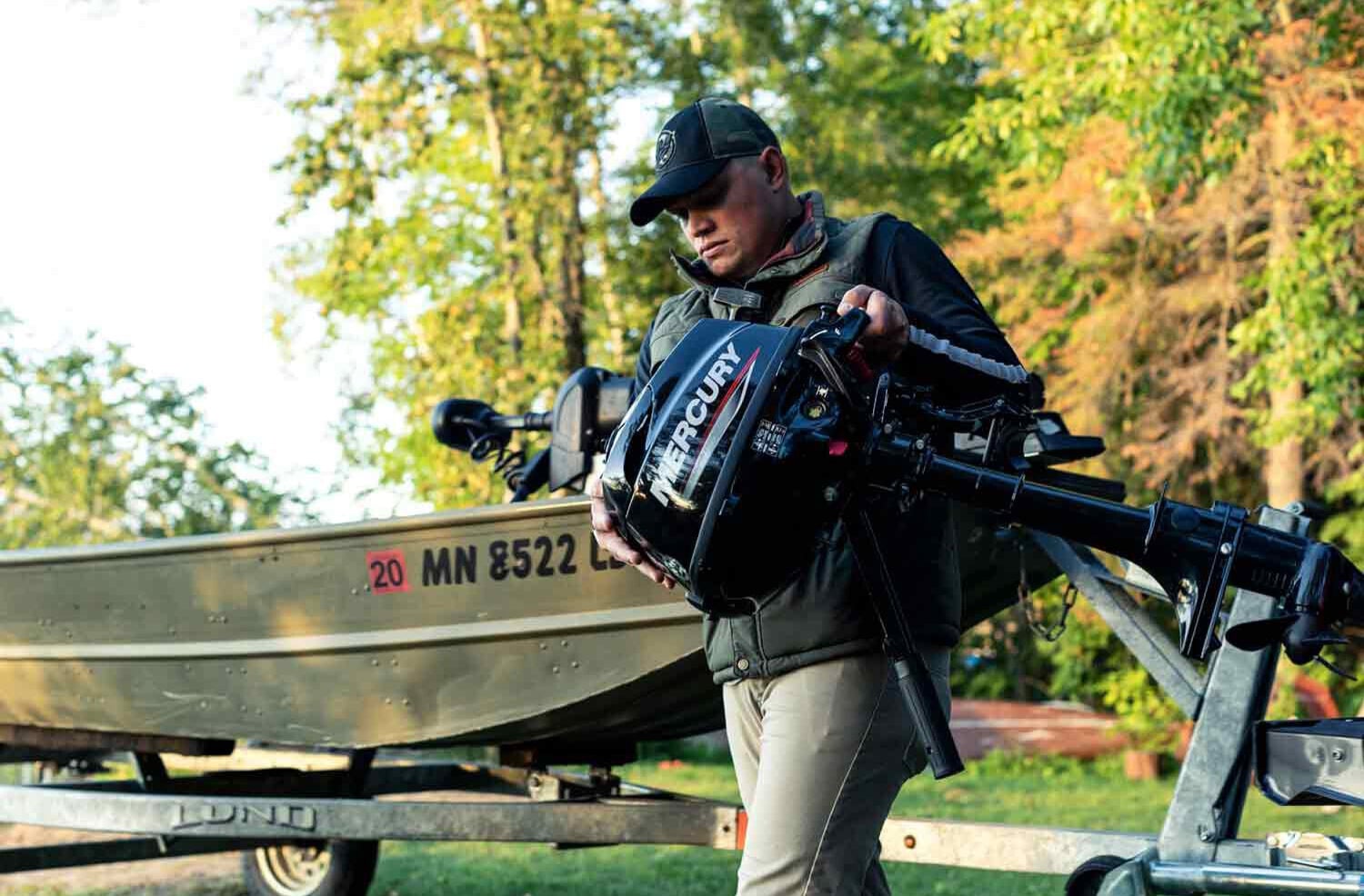 person carrying a small mercury outboard motor