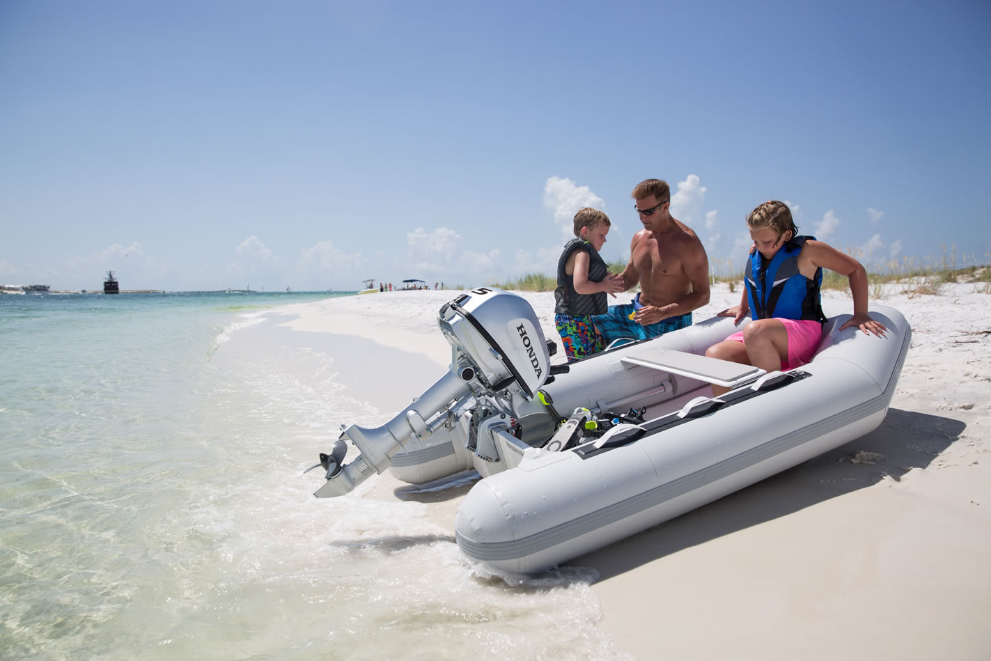 a family getting into an inflatable boat on the shore with a 5 horsepower honda outboard attached