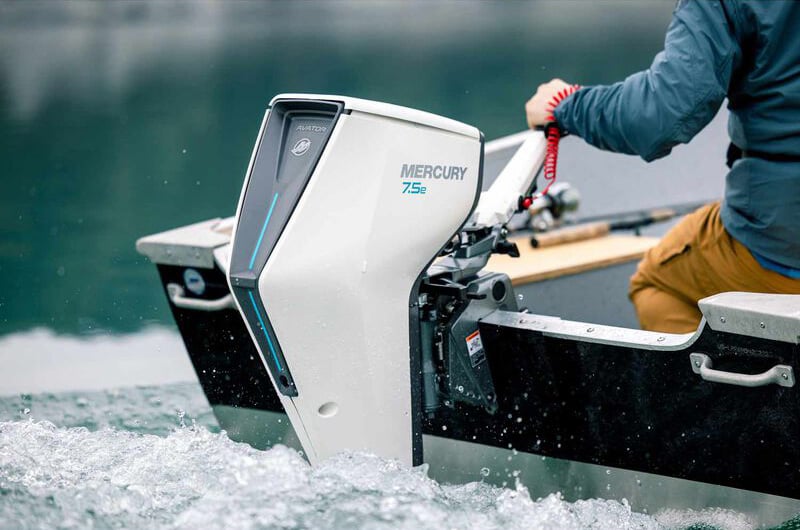 stern of small boat underway with person's hand on the throttle of an electric outboard