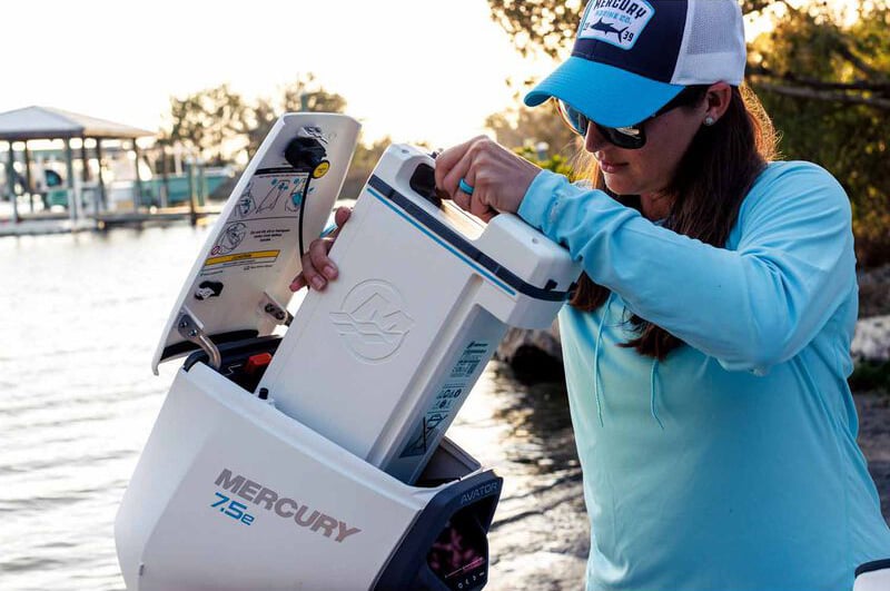 person installing a battery in an electric outboard