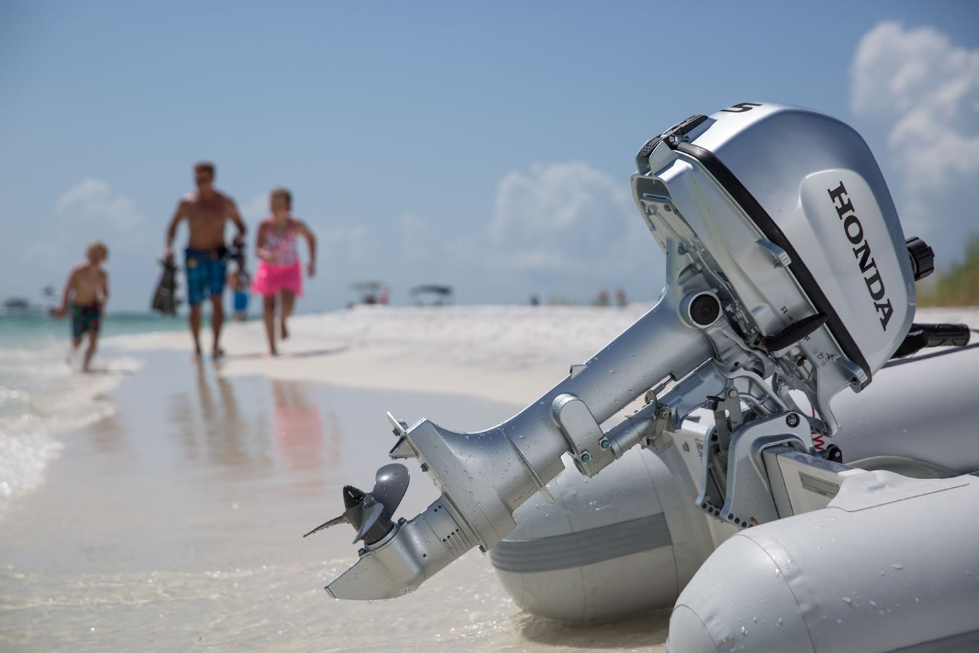a 5 horsepower honda outboard attached to an inflatable boat with a family in the background